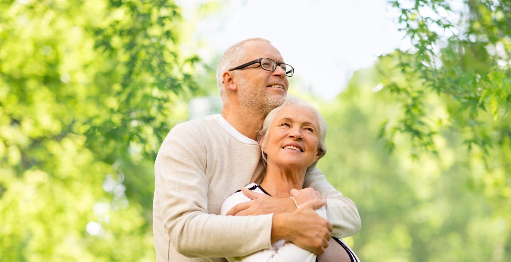 family, old age and relationships concept - happy senior couple over green natural background