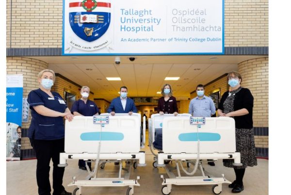 Healthcare workers in scrubs and masks stand in front of Tallaght University Hospital, posing with four hospital beds. The hospital logo is on the left, and the Beechfield Healthcare logo with a blue tree and "Better Living" text is on the right.